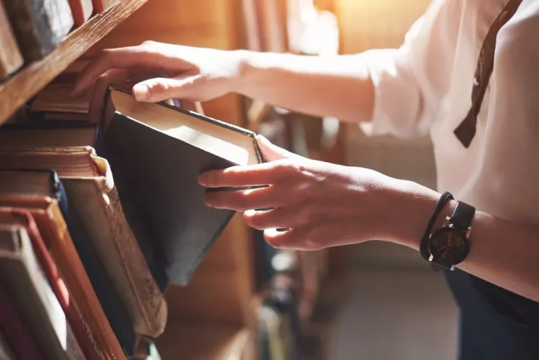 Author selecting a book from a bookshelf